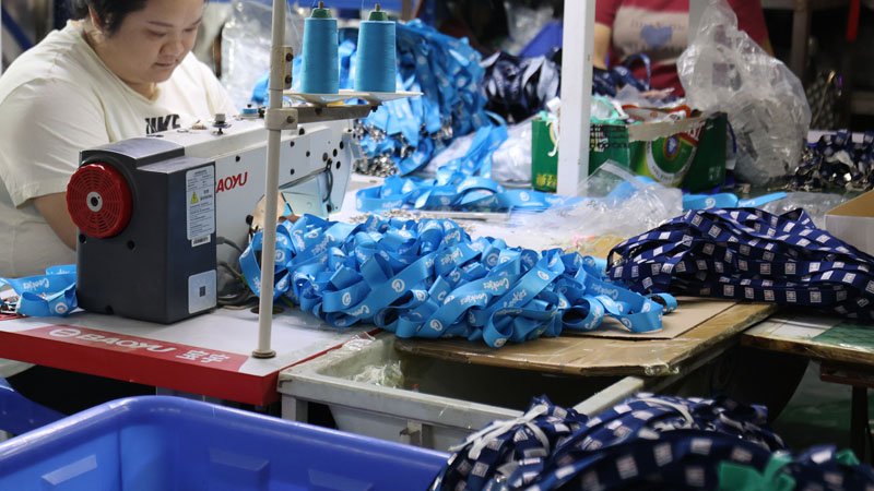 Cutting, sewing, and hardware assembly process for custom lanyards with reinforced stitching and metal clips