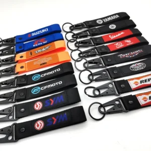 Large assortment of colorful short motorcycle key lanyards arranged in rows with sewn logo labels and black hooks