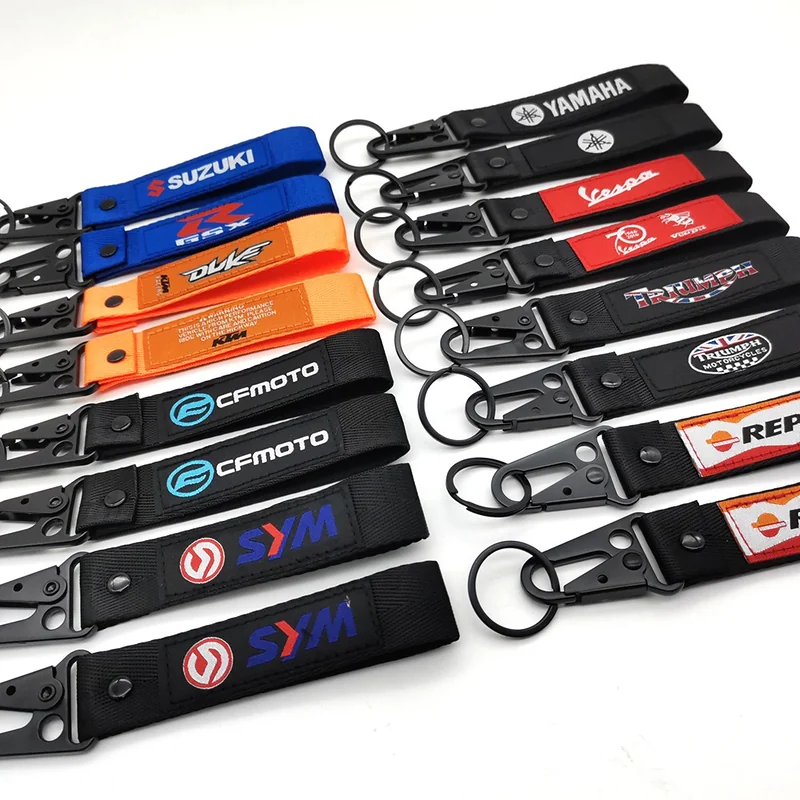 Large assortment of colorful short motorcycle key lanyards arranged in rows with sewn logo labels and black hooks