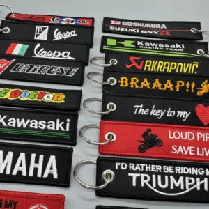 Close-up rows of black, red and green embroidered racing key tags with stitched borders, metal eyelets and split rings