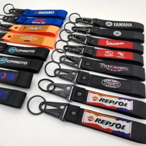 Mixed-color motorcycle key tags with sewn logo labels, split rings and black snap hooks displayed on a white background