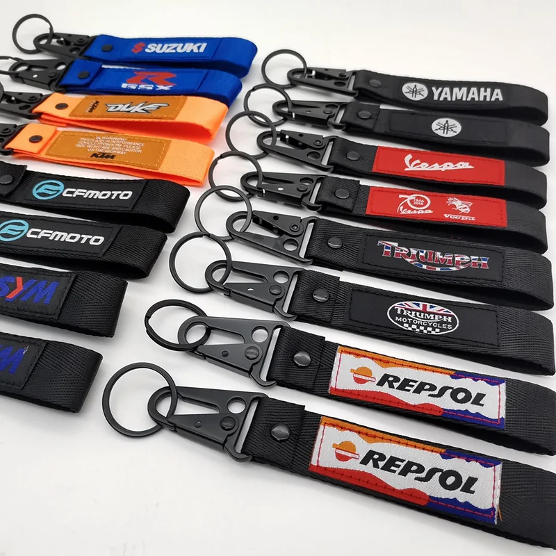 Mixed-color motorcycle key tags with sewn logo labels, split rings and black snap hooks displayed on a white background