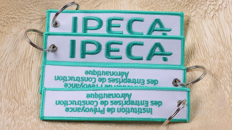Custom embroidered and woven jet tag keychains with flight tag designs and metal split rings