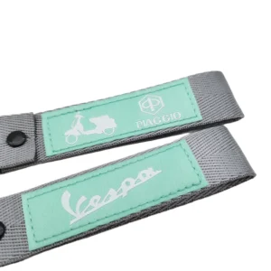 Two gray and mint green scooter key tag lanyards with sewn logo patches on a white background