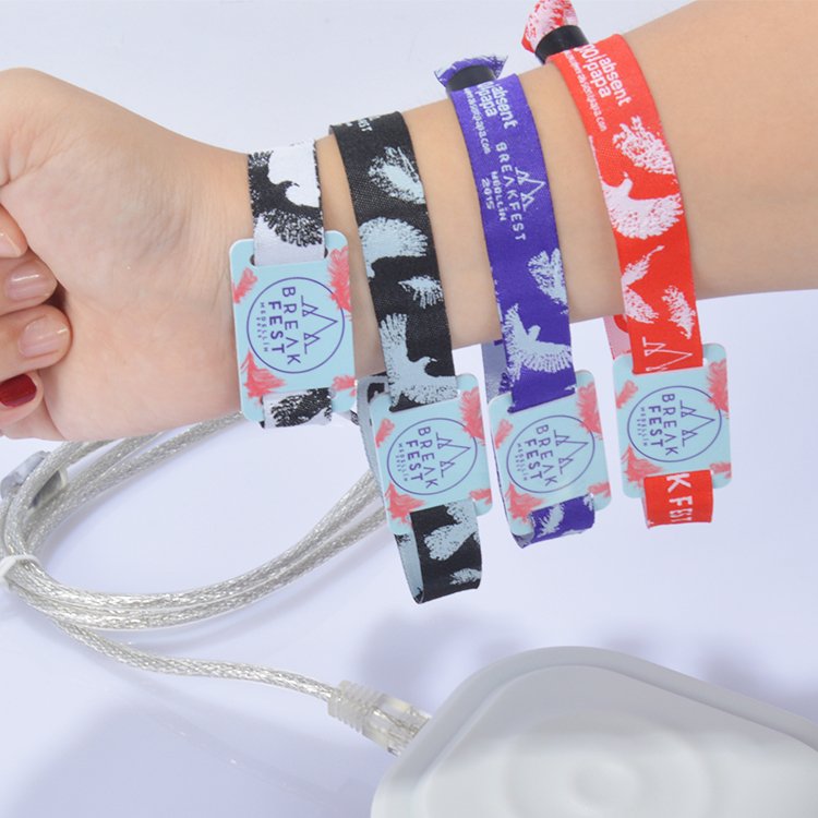 Person wearing multiple custom RFID fabric wristbands with different colors and tags