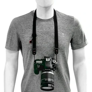 Person in a gray shirt wearing a black neck strap with a camera resting at the front