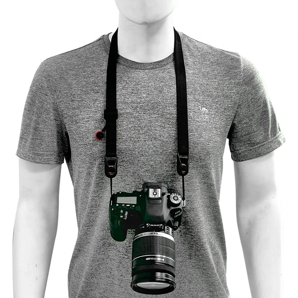 Person in a gray shirt wearing a black neck strap with a camera resting at the front