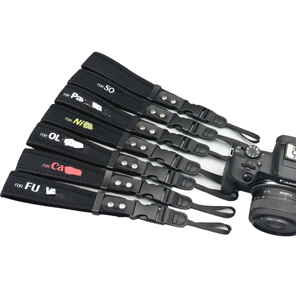 Assorted black camera straps with brand lettering, adjusters and narrow attachment ends beside a camera