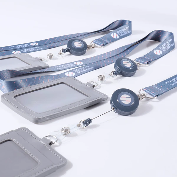 Blue printed lanyards with round badge reels and gray ID card holders