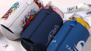 Close-up of printed can coolers holding beverage cans with stitched edges and metal lanyard clips
