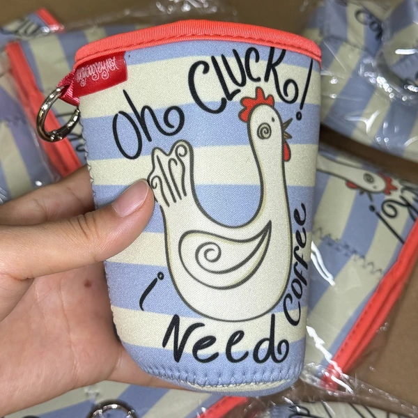 Hand holding a lidded cup in a sleeve with chicken illustration, black lettering and red upper edging