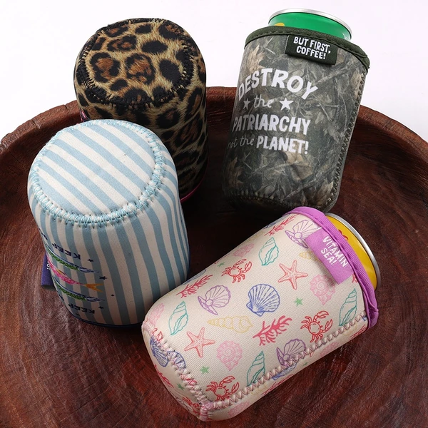 Four printed cup sleeves on a tray showing leopard, blue stripe, dark lettering and pastel patterns with stitched bases