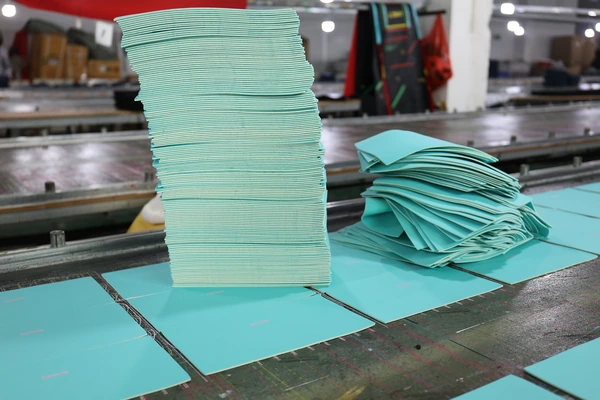 Stacked mint material sheets and cut panels on a factory table