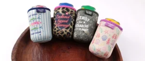 Four patterned cup sleeves holding lidded cups in striped, leopard, dark printed and pastel designs