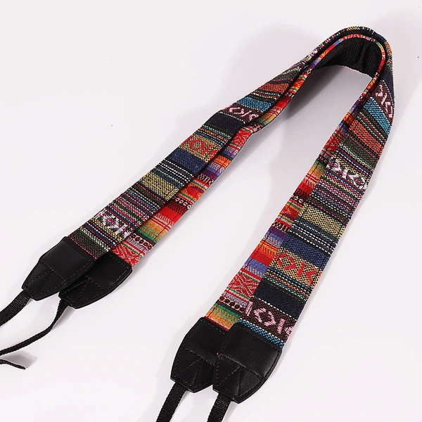 Wide camera strap with a multicolor geometric pattern, black reinforced ends and narrow black attachment webbing