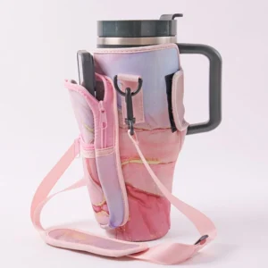 Pink marble patterned carrier around a handled tumbler with a front pocket, metal clips and pink shoulder strap