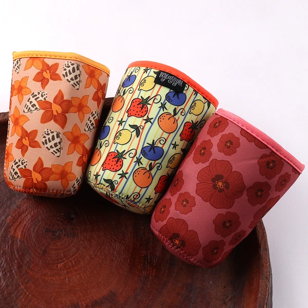Three cup sleeves with orange floral, multicolor illustrated and pink floral prints and contrasting edging