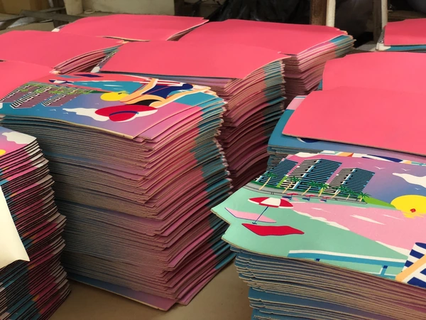 Stacks of pink and colorful printed cut panels with rounded corners on a factory table