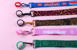 Five printed short wrist straps in blue, black, brown, pink and green with colored holder rings and clips