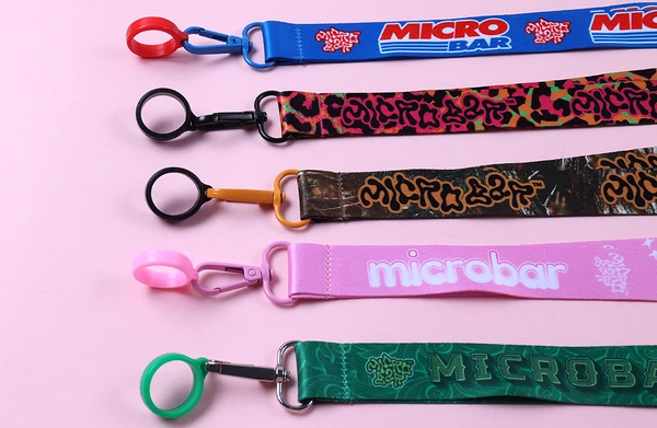 Five printed short wrist straps in blue, black, brown, pink and green with colored holder rings and clips