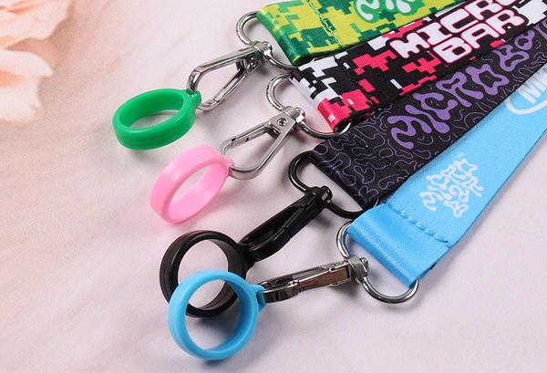 Close-up of green, pink, black and blue holder rings attached to printed straps with silver-colored swivel clips