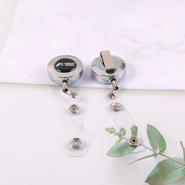 Two silver round badge reels showing logo face, back belt clip and clear snap straps