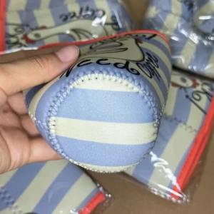 Hand holding a blue and cream striped cup sleeve with circular base and perimeter stitching visible